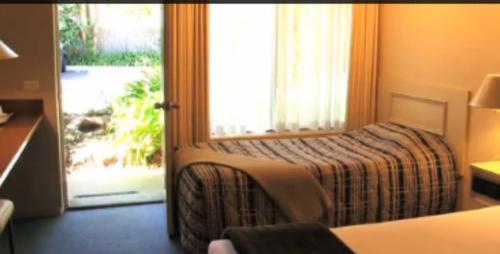 a bedroom with a bed and a sliding glass door at Clayton Monash Motor Inn & Serviced Apartments in Clayton North