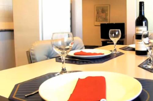 una mesa con un plato blanco y dos copas de vino en Clayton Monash Motor Inn & Serviced Apartments, en Clayton North