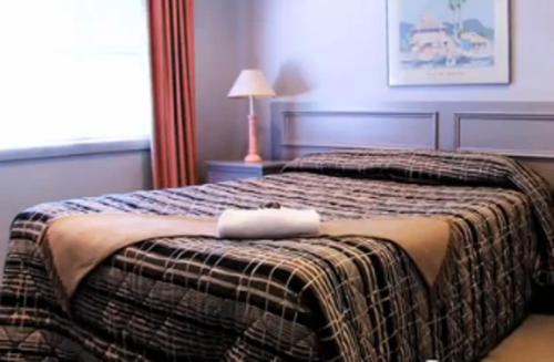a bedroom with a bed with a blanket and a lamp at Clayton Monash Motor Inn & Serviced Apartments in Clayton North