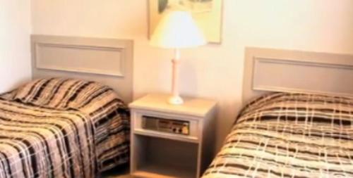 a bedroom with two beds and a lamp on a night stand at Clayton Monash Motor Inn & Serviced Apartments in Clayton North