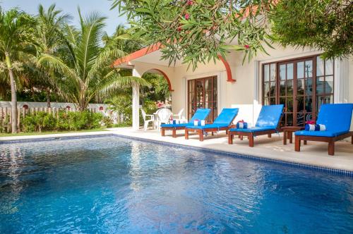 a swimming pool with blue chairs and a house at Casa Anita - Relaxing Home Steps from the Puerto Morelos Beach in Puerto Morelos