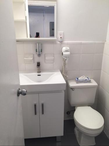 a white bathroom with a toilet and a sink at Ocean Front Units at Miami Beach in Miami Beach