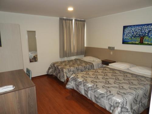 a hotel room with two beds and a table at Nice Inn Tacna in Tacna