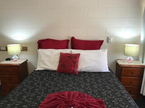 a bedroom with a bed with red and white pillows at The Lodge Outback Motel in Broken Hill