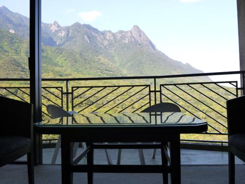a table on a balcony with a view of mountains at Yakushima Iwasaki Hotel in Yakushima