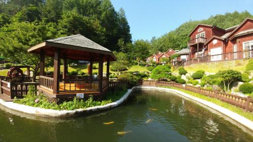 a gazebo next to a pond in a house at Sisilli Pension in Pyeongchang 