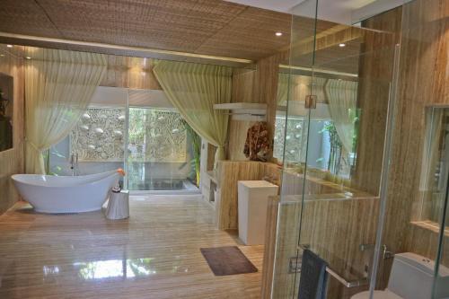 ein Badezimmer mit Badewanne und Glasdusche in der Unterkunft Grand Mega Resort & Spa in Cepu