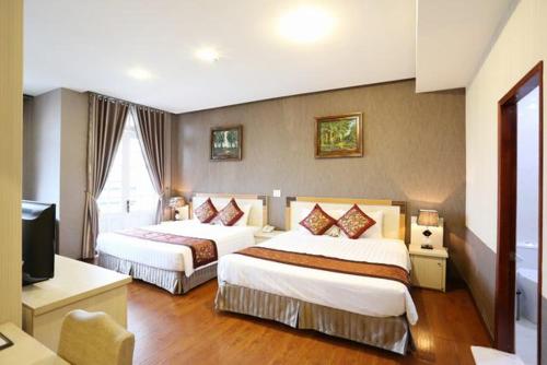 ein Hotelzimmer mit 2 Betten und einem TV in der Unterkunft Mountain Town Hotel in Da Lat