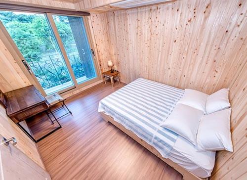 a bedroom with a bed and a large window at Dongbackdongsan Pension in Jeju