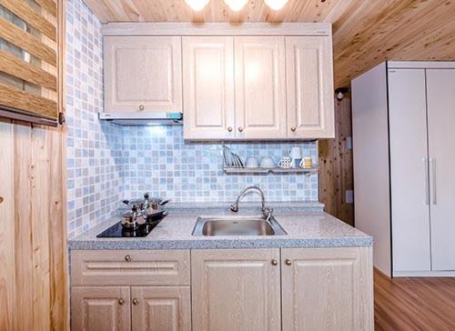a kitchen with a sink and a white refrigerator at Dongbackdongsan Pension in Jeju