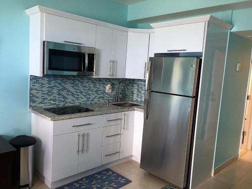 a kitchen with white cabinets and a stainless steel refrigerator at Ocean Front Units at Miami Beach in Miami Beach
