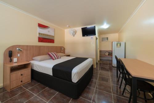 a hotel room with a bed and a table and a kitchen at Winter Sun Motel in Rockhampton