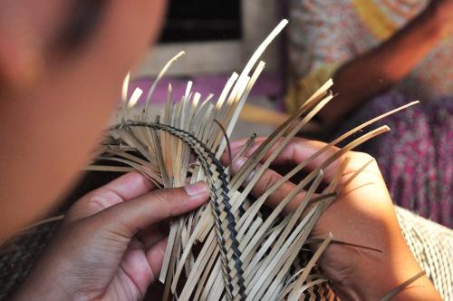a person holding a bunch of bamboo sticks at Mu Homestay in Tetebatu