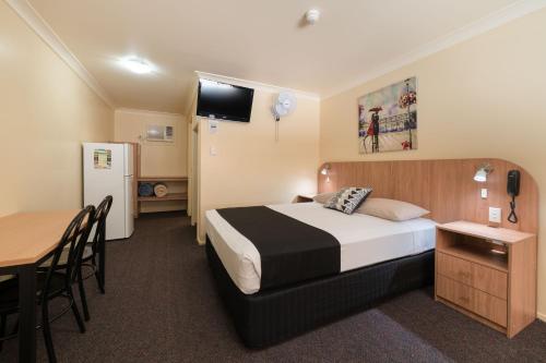 a hotel room with a bed and a table and a refrigerator at Winter Sun Motel in Rockhampton