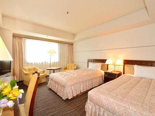 a hotel room with two beds and a table with flowers at Grand Hotel Hamamatsu in Hamamatsu