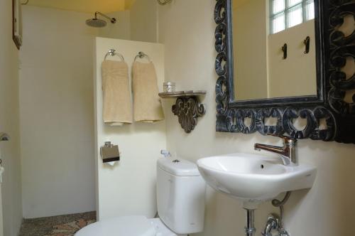 a bathroom with a sink and a toilet and a mirror at Villa Mangga in Ubud