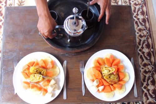 a table with two plates of fruit and a juicer at Mu Homestay in Tetebatu