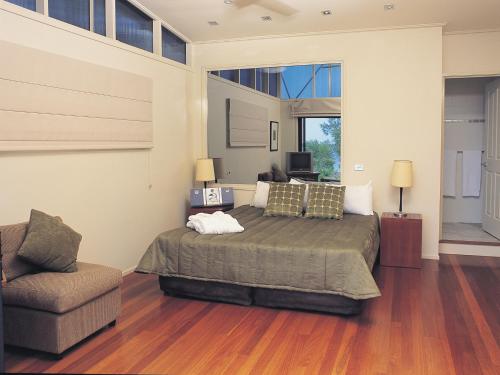 Un dormitorio con una cama grande y una silla. en NRMA Myall Shores Holiday Park, en Bulahdelah
