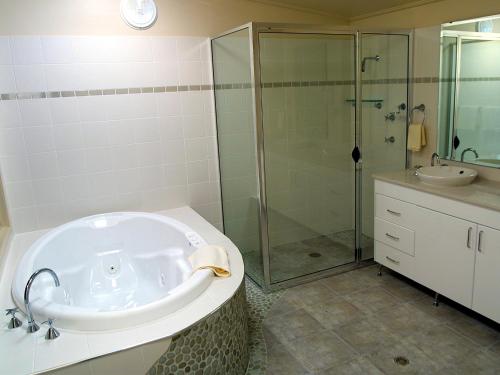 een badkamer met een bad, een douche en een wastafel bij NRMA Myall Shores Holiday Park in Bulahdelah