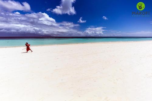 a person walking on a beach near the ocean at Makofi Guest House in Nungwi