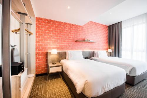 a hotel room with two beds and a brick wall at The Smith House in Pantai Cenang