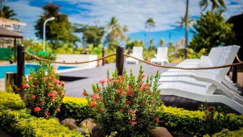 a group of white benches in a park with flowers at Tanoa Rakiraki Hotel in Rakiraki