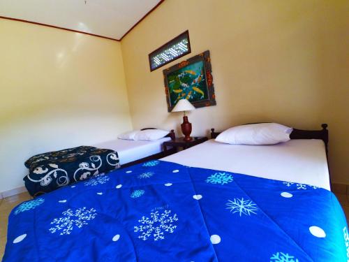 Pondok Batur Indah Homestay Karangasem في Tirtagangga: سريرين توأم في غرفة ذات بطانية زرقاء