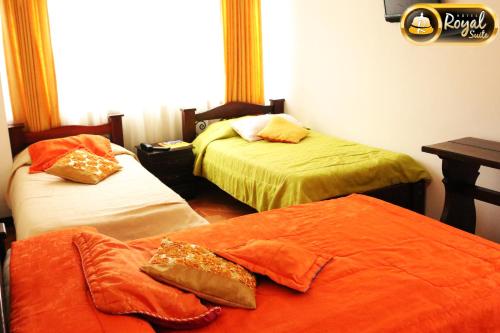 a room with two beds with orange sheets at Hotel Royal Suite in Manizales