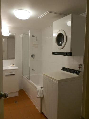 a white bathroom with a shower and a sink at Chasely Apartment Hotel in Brisbane