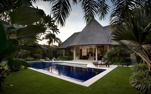 a house with a swimming pool in front of a house at The Kunja Villa-Hotel in Seminyak
