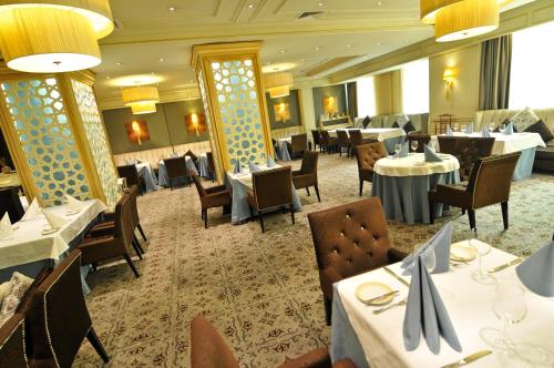 a dining room with white tables and chairs and tablesearcher at Grand Tien Shan Hotel in Almaty