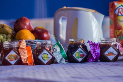 a table topped with jars of jam and a basket of fruit at Haveli Kalwara - A Heritage Hotel in Jaipur