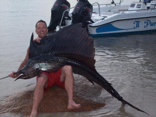 a man holding a large fish in the water at Mirella Villa Holiday Apartment in Anse Possession