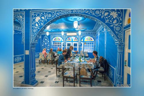 a group of people sitting at a table in a blue room at Haveli Kalwara - A Heritage Hotel in Jaipur