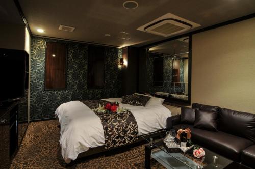 een hotelkamer met 2 bedden en een bank bij Hotel Grande (Love Hotel) in Kitakyushu