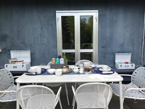 a white table with white chairs and a table with bowls and plates at La Casa Blu di Monasteto in Tricesimo