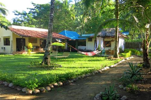 a house with a hammock in the yard at BLU MA RE GUESTHOUSE - Sugar Beach in Sipalay