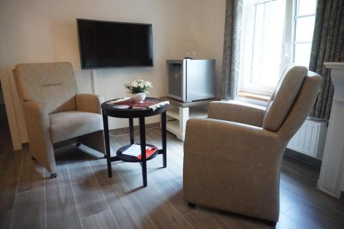 a living room with a chair and a table and a tv at B&B Domein Rodin in Oud-Turnhout