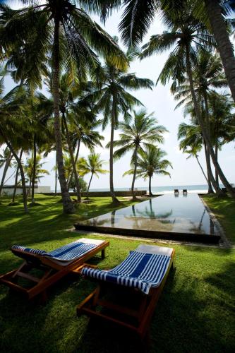 a pool with palm trees and a bench and a table at Apa Villa Thalpe in Unawatuna