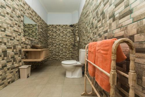 ein Badezimmer mit Toilette und einer Ziegelwand in der Unterkunft Castro Villa in Seminyak