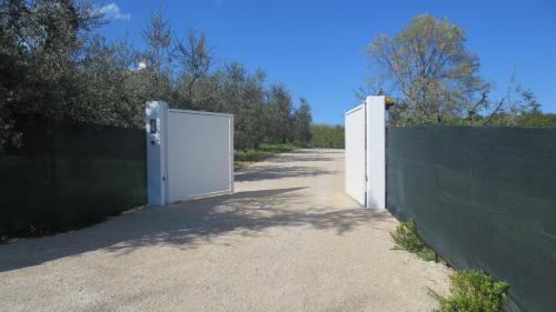 a white door in a fence next to a dirt road at B&B Casa Soresina in Offagna