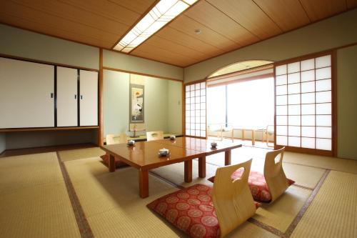 a dining room with a table and chairs and windows at Kikuchi Kanko Hotel in Kikuchi