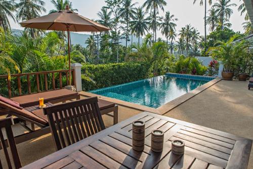 a swimming pool with a table and an umbrella at Tropical Season Villa Resort in Mae Nam