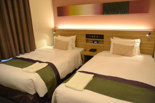 a hotel room with two beds with white and green sheets at Rembrandt Style Tokyo Nishikasai Grande in Tokyo