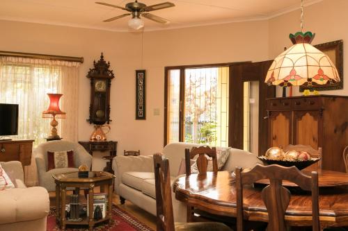 a living room with a table and chairs and a clock at Beau & I in Graaff-Reinet
