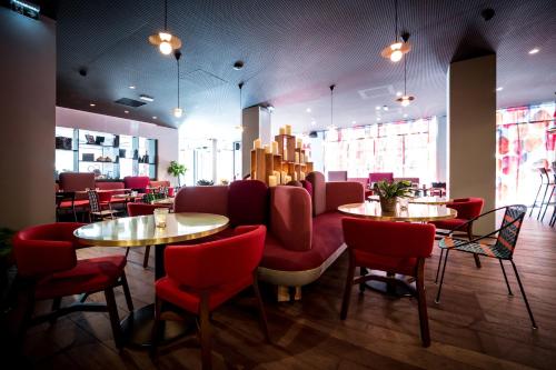 a restaurant with two tables and red chairs at BOMA easy living hotel in Strasbourg