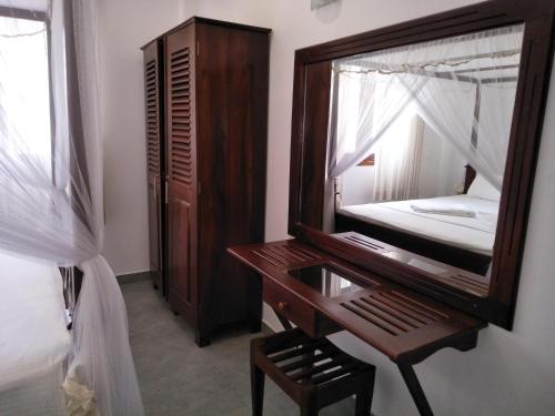 a bedroom with a mirror and a desk and a bed at Villa Red Lobster in Hikkaduwa