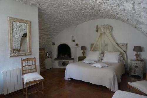 um quarto com uma cama branca e uma lareira em La Vieille Bergerie em Èze