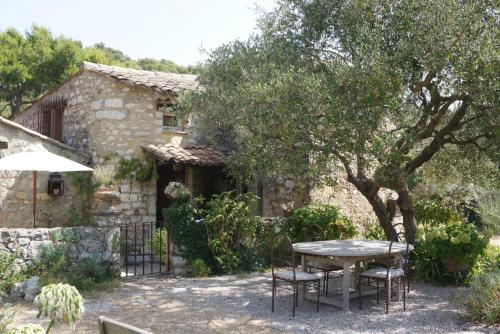 a table and chairs in front of a stone house at La Vieille Bergerie in Éze