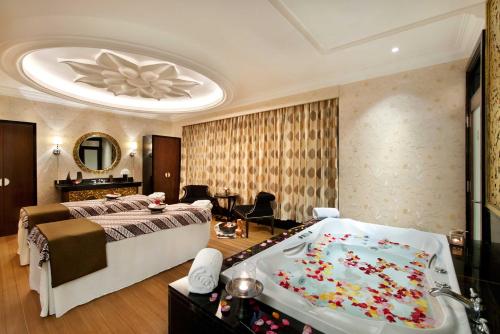 a bedroom with a large bed and a bath tub at The Trans Luxury Hotel Bandung in Bandung